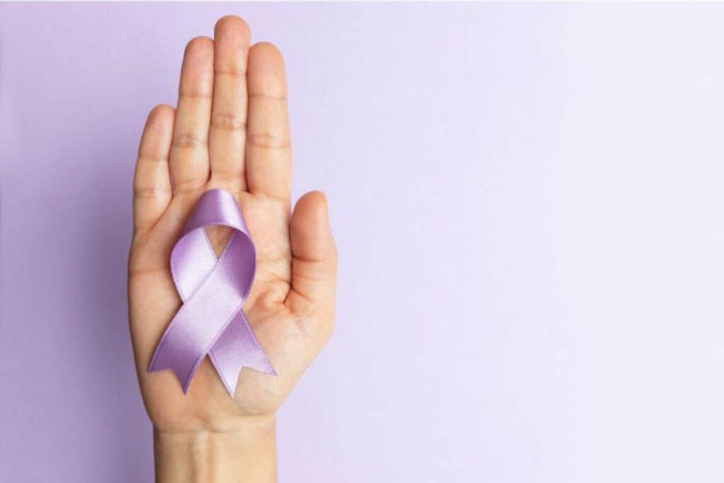 A hand holding a purple ribbon